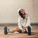 girl in white hoodie and white pants sitting on brown wooden floor
