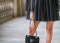 a woman in a black dress holding a black purse