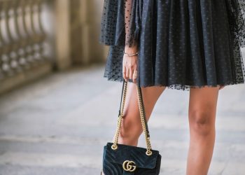 a woman in a black dress holding a black purse