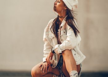 a woman sitting on the ground wearing a white hat