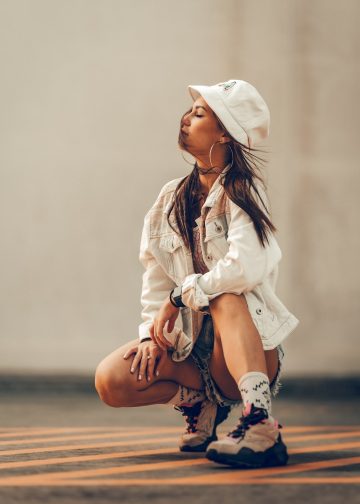 a woman sitting on the ground wearing a white hat
