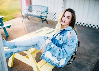 smiling woman sitting on yellow picnic table during daytime