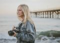 woman holding camera standing on seashore