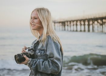 woman holding camera standing on seashore