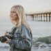 woman holding camera standing on seashore