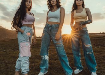 2 women in white tank top and blue denim jeans standing on brown field during daytime